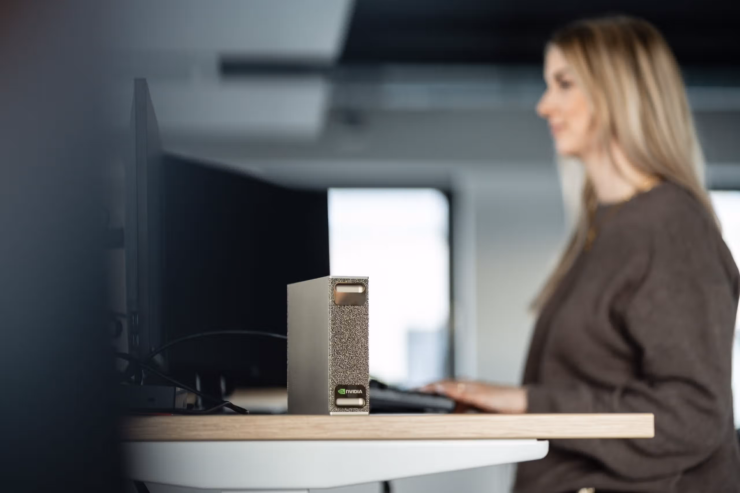 Kollegin am Arbeitsplatz mit der AI.Box-Hardware auf dem Schreibtisch
