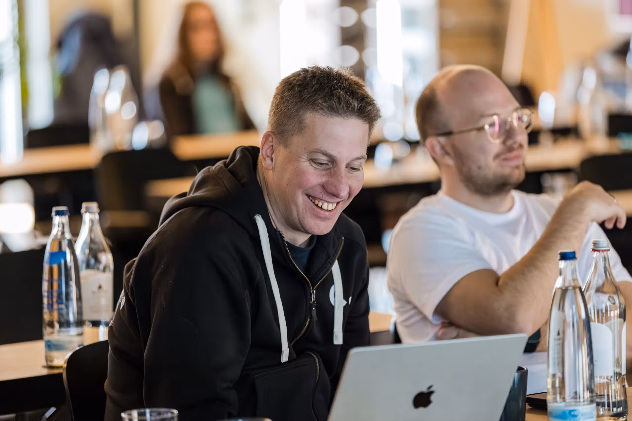 Zwei Conciso-Kollegen am Laptop, einer lacht während eines Workshops