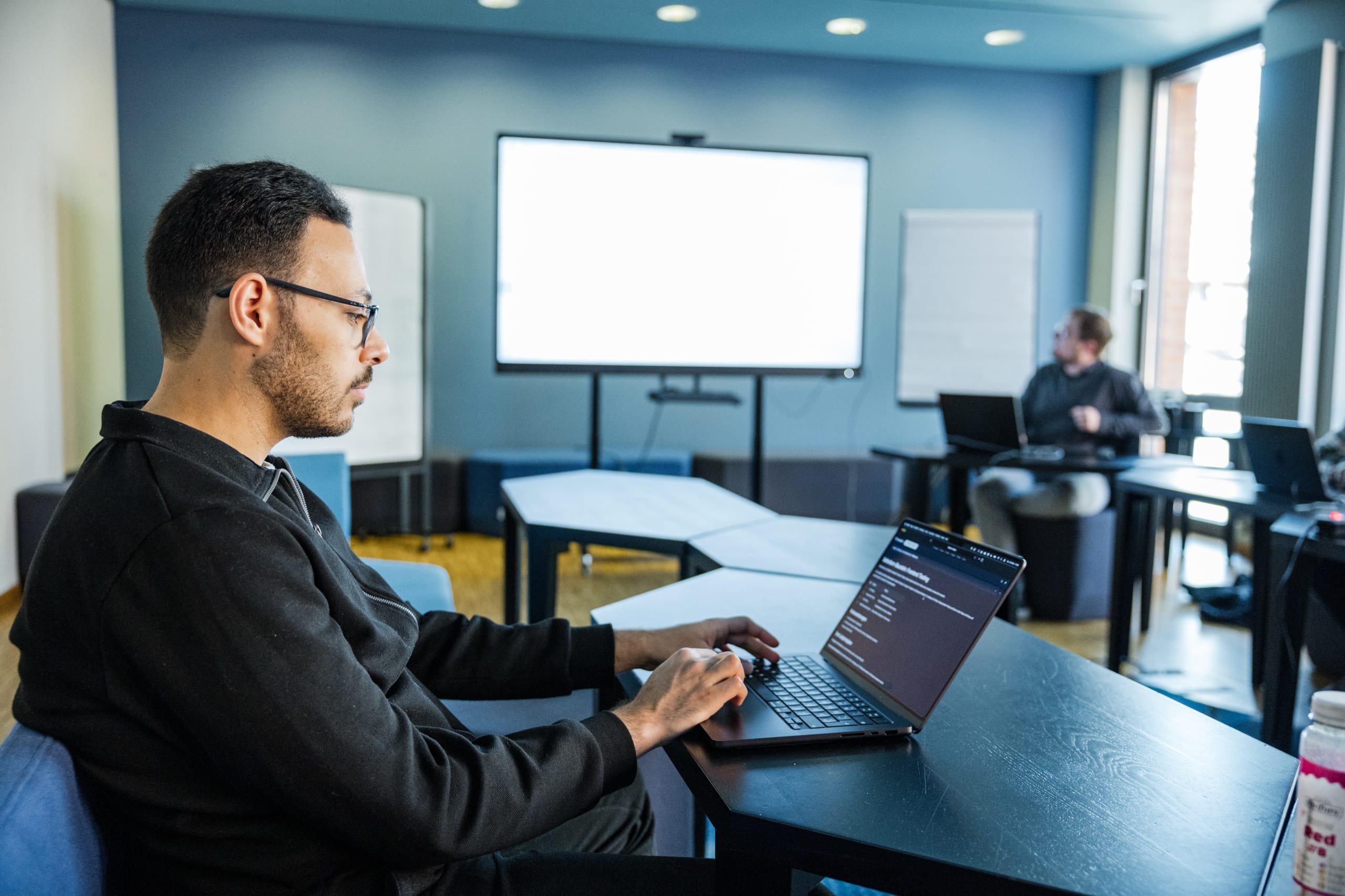 Conciso-Entwickler arbeitet konzentriert am Laptop im Meetingraum