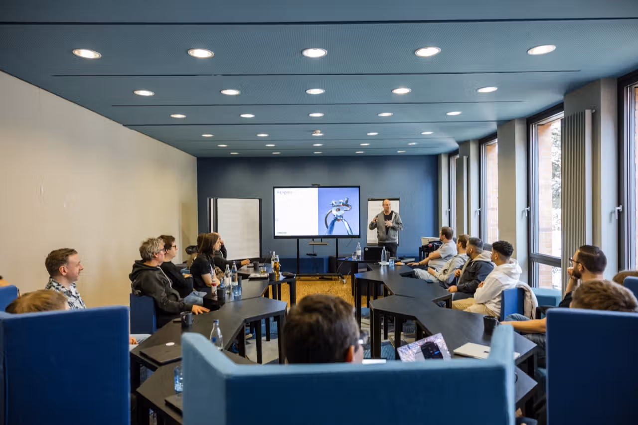 Conciso-Kollege präsentiert vor dem Team im blau gestalteten Seminarraum