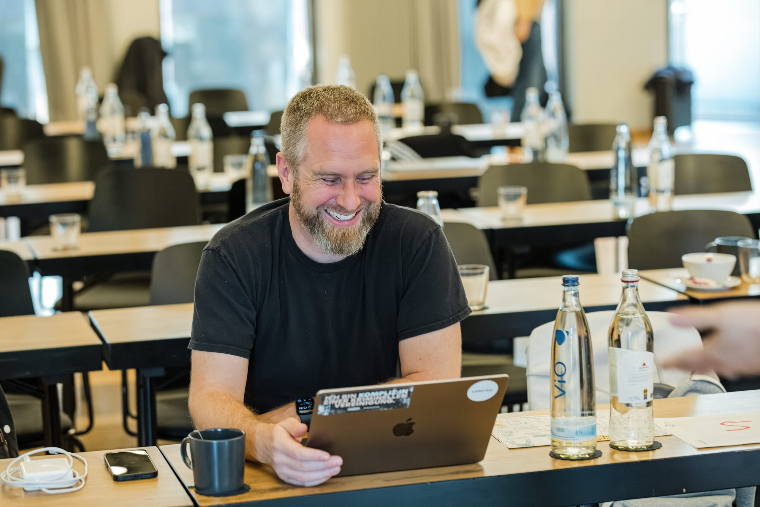 Lachender Conciso-Kollege am Laptop während eines Workshops