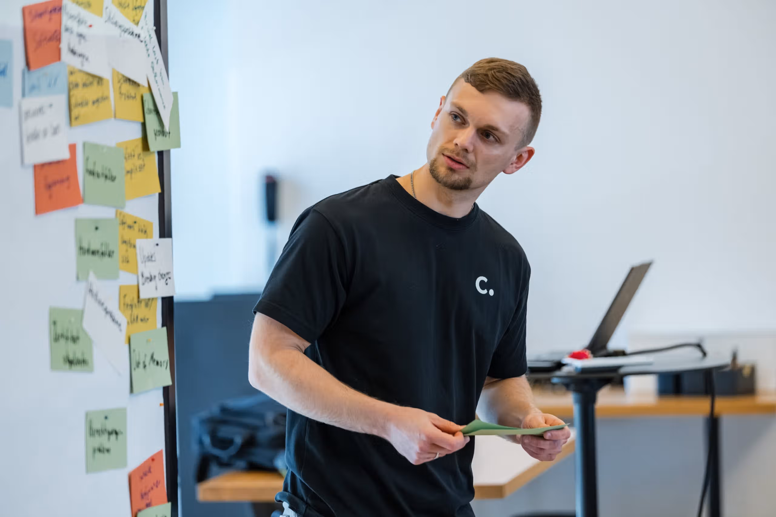 Conciso-Kollege präsentiert im Workshop vor einem Whiteboard voller Haftnotizen